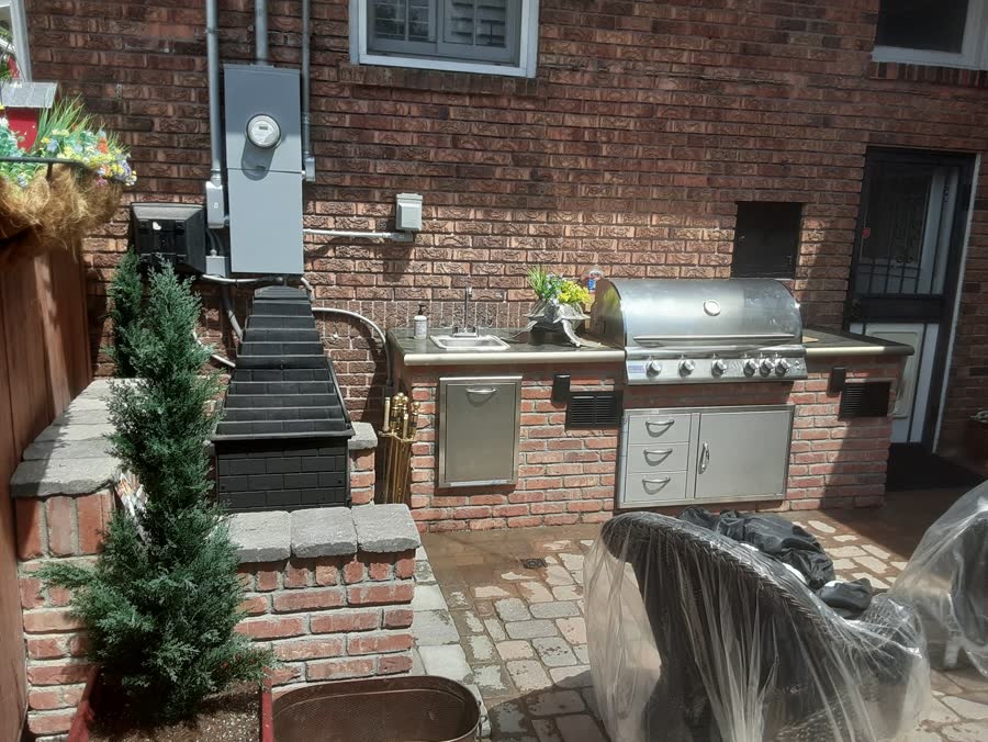 Brick outdoor kitchen built around a grill and sink