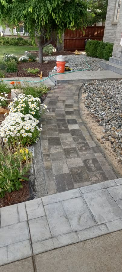 A paver walkway curving between flower beds