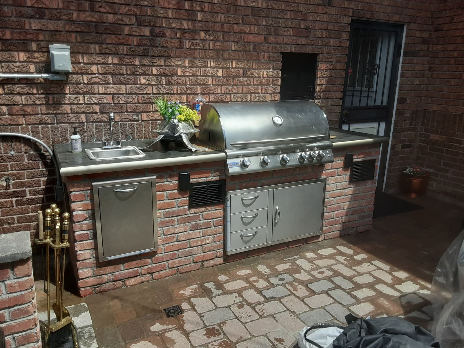 Built in brick outdoor kitchen with a stainless grill and sink