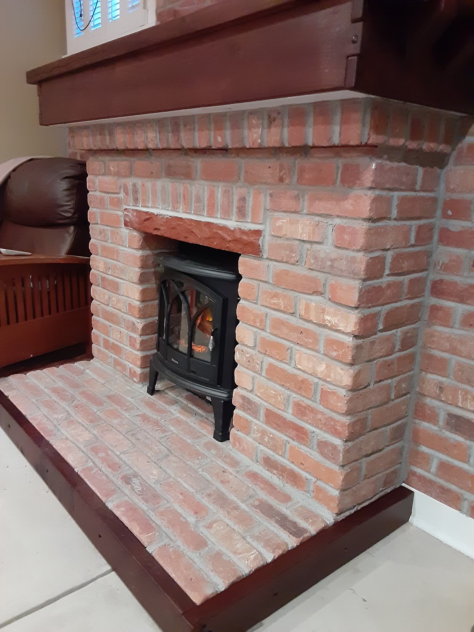 Red brick fireplace and hearth around a wood stove