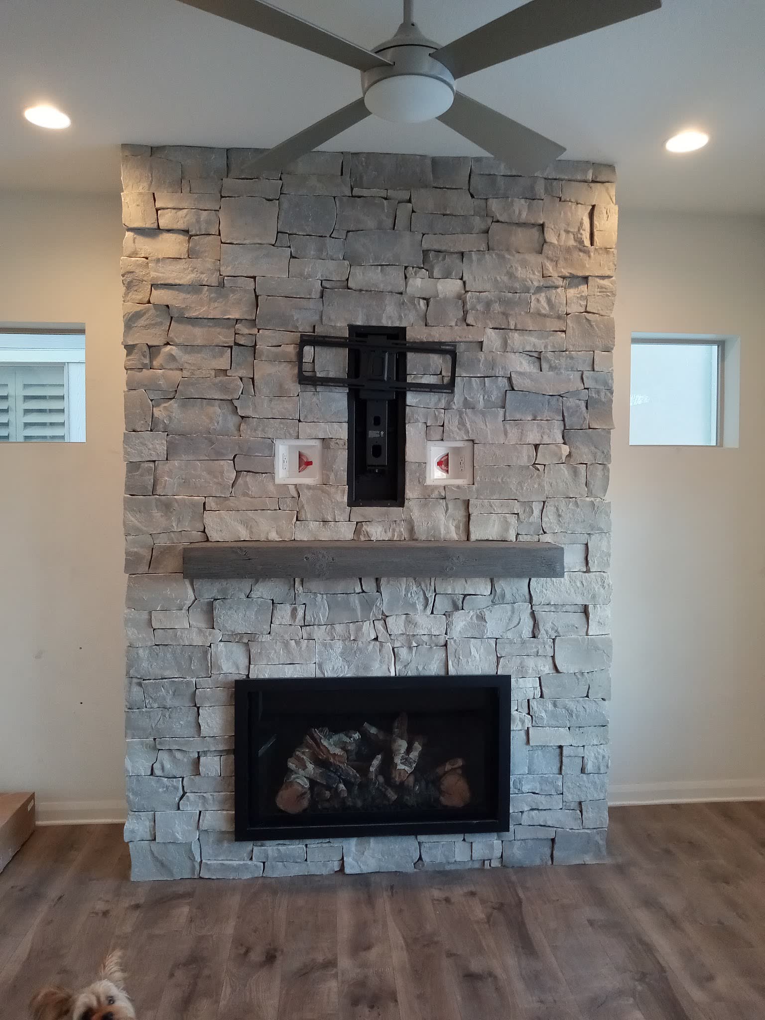 Finished stacked stone fireplace with a reclaimed timber mantel